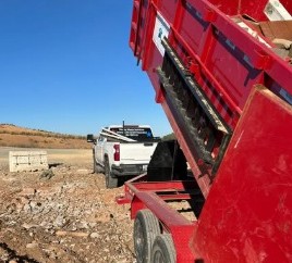 Red dump trailer bed raised on a job site