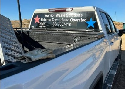 Rear window of the Warrior Waste truck reading Veteran Owned and Operated